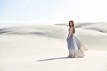 Image showing Fashion, dress of woman in the desert and wind isolated around sand. Travel or freedom, holiday or vacation and female person and portrait of goddess on adventure with mockup space outdoor in summer