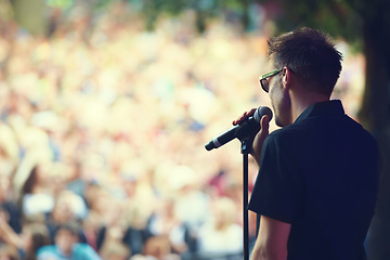 Image showing Music, microphone and concert with man at festival for rock, performance and party in nature. Celebration, energy and audience with male singer on stage for club, rave and dj event in outdoors