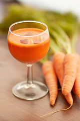 Image showing Vegetable, carrot juice and healthy food with color, art and creativity for nutritionist menu. Vegan smoothie drink in glass for wellness, diet or nutrition on a wooden table with ingredients