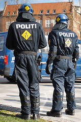 Image showing Security, riot and protest with police officer in city for law enforcement, protection or safety. Brave, uniform and government with people in street for demonstration rally, human rights or control