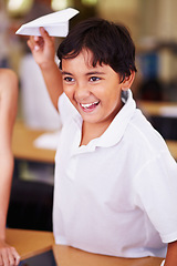 Image showing School, classroom and a boy playing with a paper airplane while learning for education or child development. Study, children and growth with a male student having fun in an elementary class for kids