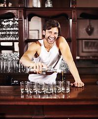 Image showing Portrait, whisky and alcohol with a handsome barman behind the counter of a pub to serve drinks during happy hour. Smile, glass and drink with a man bartender pouring a whiskey beverage in a bar