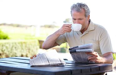 Image showing Relax, coffee and newspaper with man in park for lunch break, summer and calm. News, nature and morning with senior person in outdoors reading at picnic table for retirement, tea and crossword