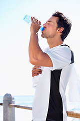 Image showing Man, fitness and drinking water for hydration, health or wellness after workout, exercise or training at the beach. Fit, active and thirsty male having a drink in break or refreshment from exercising