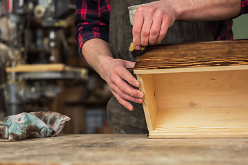 Image showing Carpenter painting wooden