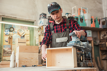 Image showing Worker grinds the wood box