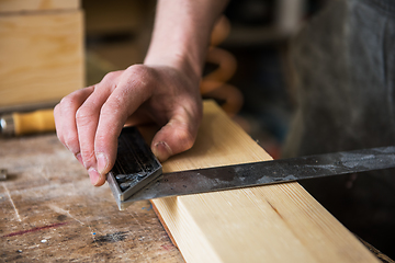 Image showing The worker makes measurements of a wooden board