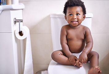 Image showing African baby boy, toilet and home with smile, learning and childhood development for potty training. Young toddler, black child or kid sitting in bathroom with diaper, growth and looking in house