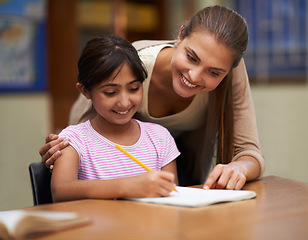 Image showing School, study or learning with a student and teacher in a classroom together for writing or child development. Education, scholarship and teaching with a woman tutor helping a girl child in class