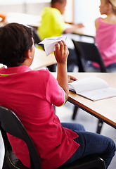 Image showing Bully, boy child with paper plane in classroom and sitting at his desk with behavior problem. Naughty or bad, distracted male student in class and playing with prank in school building on chair