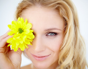 Image showing Beauty, portrait and woman with a flower in a studio with a cosmetic, natural and face routine. Happy, smile and young female model with a yellow floral plant for facial isolated by white background.