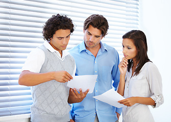 Image showing Business people, documents and planning in meeting for teamwork, strategy or serious brainstorming at office. Group of concerned employees working on paperwork, problem solving or tasks at workplace