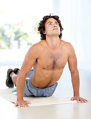 Image showing Yoga, man and cobra stretch in home for health, wellness and flexibility in house. Pilates, stretching and male person, yogi or athlete training, holistic workout and exercising for fitness on mat.