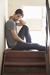 Image showing Thinking, depression and lonely with a man on a staircase in his home, sitting on the landing by a window. Idea, mental health and relax with a handsome young male on steps or stairs in his house