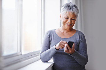 Image showing Window, app and senior woman with a smartphone, connection and typing for social media at home. Mature lady, female person and model with a cellphone, communication and online reading with texting