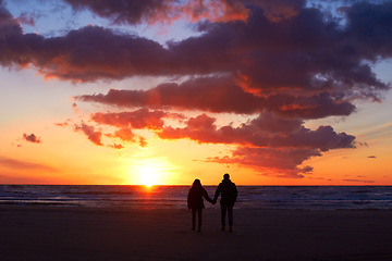 Image showing Silhouette, couple holding hands at sunset and on beach walking together. Love or care, holiday or vacation and shadows of people on the seashore for embrace for romance date or honeymoon outdoor