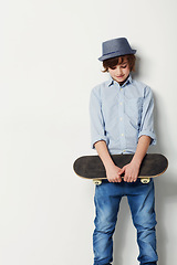 Image showing Skateboard, young boy with a hat and mockup in studio background with space. Trendy fashion or casual wear, confident or cool and isolated person posing for clothing advertisement in backdrop