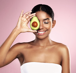 Image showing Avocado, happy woman and healthy beauty in studio, pink background and aesthetic glow. African model, natural skincare and organic cosmetics for sustainability, vegan dermatology and facial nutrition