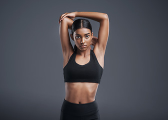 Image showing Portrait, mockup and stretching with a sports woman in studio on a gray background for fitness or health. Exercise, workout and warm up with an attractive young female athlete training her body