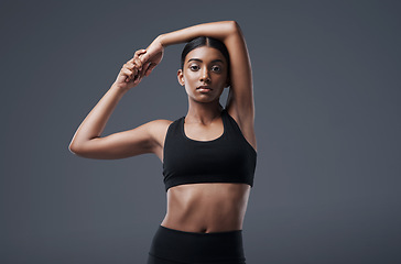 Image showing Portrait, mockup space and stretching with a woman in studio on a gray background for exercise or health. Fitness, workout and warm up with an attractive young female athlete training her body