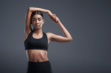 Image showing Portrait, mockup space and warm up with an athlete woman in studio on a gray background for exercise or health. Fitness, workout and stretch with an attractive young female model training her body