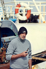 Image showing Fisherman boat, mature man portrait and smoking pipe by the sea water at a port for fishing. Old man, ocean and senior dock worker sitting by boats outdoor with tobacco smoke at a harbor for work