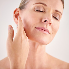 Image showing Face, beauty and skincare with a senior woman in studio on a gray background for natural antiaging treatment. Facial, skin care and wellness with an attractive mature female model touching her cheek