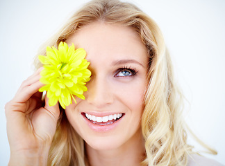 Image showing Beauty, makeup and female model with a flower in studio with a cosmetic, natural and face routine. Happy, smile and closeup of young woman with yellow floral spring plant isolated by white background