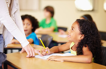 Image showing Child, writing and hand of teacher teaching student at school for education, learning or development. Woman and happy girl with notebook, pencil and knowledge at classroom desk with support and smile