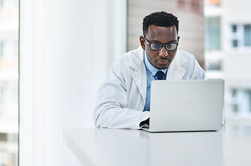 Image showing Healthcare, research and man doctor on laptop in consultation office for reading in hospital. Online, medical and African male health expert checking medical news, development or clinic schedule