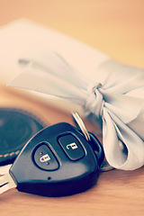 Image showing Ribbon, present and keys for new car on table for surprise, gifts and birthday present for driver. Travel mockup, transport and closeup of vehicle key with bow for loan, motor investment and reward