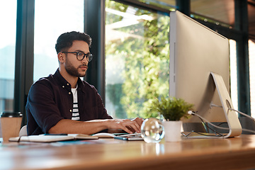 Image showing Computer, serious and a business man typing and working at desk while online for research or creative work. Male entrepreneur person with glasses for reading or writing email with internet connection