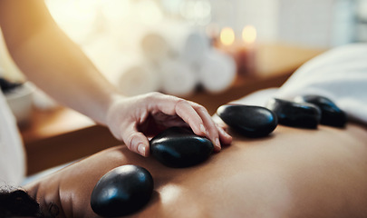 Image showing Woman, hands and rocks in relax for back massage, skincare or beauty relaxation on bed at spa. Hand of masseuse applying hot rock or stones on female for physical therapy or treatment at a resort