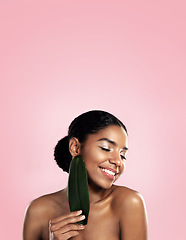 Image showing Happy woman, skincare and natural leaf in studio, pink background and space for eco friendly cosmetics. Face, african model and beauty from green plants, leaves and sustainability of vegan aesthetic