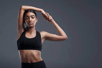 Image showing Portrait, mockup and stretch with a sporty woman in studio on a gray background for fitness or health. Exercise, workout and warm up with a young focused indian female athlete training her body