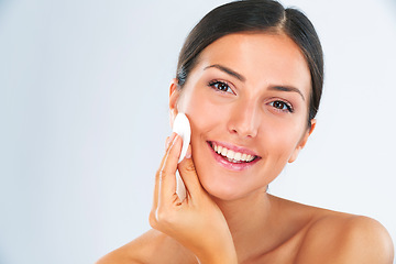 Image showing Skincare, portrait and woman with a cotton pad in studio for a beauty, natural and face routine. Health, wellness and happy female model with health, wellness and cosmetic product by gray background.