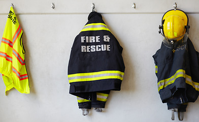 Image showing Fireman, uniform and clothing hanging on wall rack at station for fire fighting protection. Firefighter gear, rescue jacket and helmet with reflector for emergency services, equipment or department