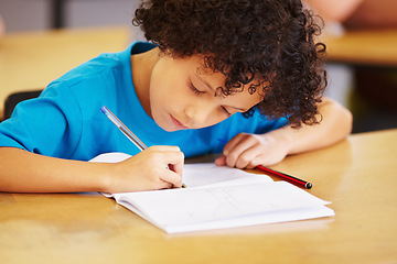 Image showing Boy, writing and book in school classroom for learning, focus or development for future. Male child, pen and paper for studying, education and test for thinking, scholarship or concentration in class