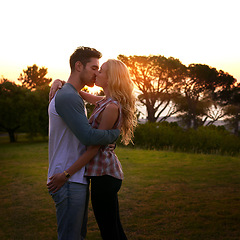 Image showing Couple kiss, nature and trees in sunset with love, romance and date on adventure, travel or honeymoon. Man, woman and kissing with hug, care and outdoor for safari, freedom or holiday in countryside