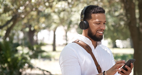 Image showing Businessman, typing and phone music in nature, communication and chat in the morning. Smile, young and employee listening to a podcast, radio or streaming audio on a mobile in a park for a commute