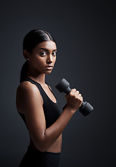 Image showing Portrait, serious and woman with dumbbell for workout in studio isolated on a black background. Strong, bodybuilder and Indian female athlete weightlifting for muscle, training and fitness exercise.