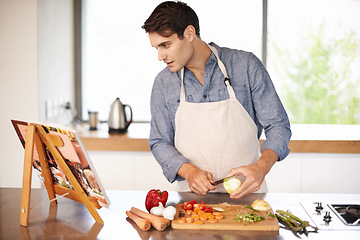 Image showing Cooking, man and cookbook in a kitchen with food, vegetables and ingredients for meal. Reading, male person and healthy diet in a house for nutrition eating and chef learning with a book and knife