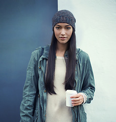 Image showing Portrait of a woman with a cup of coffee by a wall with a casual, trendy and stylish outfit. Beautiful, gen z and young female person with takeaway warm beverage and cool fashion or style in the city