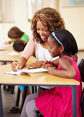 Image showing Helping, teaching and teacher with child at school for education, learning or development. Happy black woman talking to student about lesson, writing and knowledge at a classroom desk with support