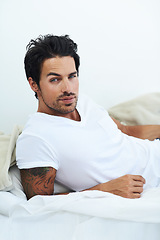 Image showing Portrait, relax and bed with a sexy man in the morning on a white background looking casual after wake up. Fashion and confidence with a handsome young male model lying in the bedroom of his home