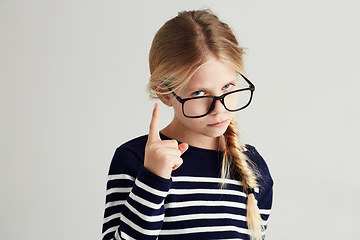Image showing Strict, serious and portrait of a child with a gesture isolated on a white background in a studio. Rude, smart and a young girl wearing glasses and gesturing with finger for discipline on a backdrop