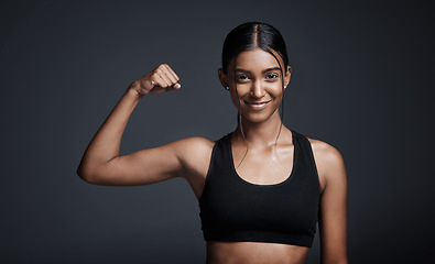 Image showing Portrait, smile and woman flexing muscle in studio isolated on black background. Strong, happy and Indian female athlete with bicep, arm strength and bodybuilder workout, fitness or sports exercise.