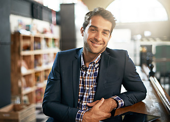 Image showing Portrait, relax and happy with a man in a coffee shop, sitting at a bar counter as a customer during the day. Cafe, smile and fashion with a handsome young male consumer in a trendy restaurant