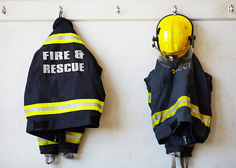 Image showing Firefighter, uniform and clothing hanging on wall rack at station for fire fighting protection. Fireman gear, rescue jacket and helmet with reflector for emergency services, equipment or department