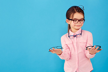 Image showing Happy, decision and a girl with optometry glasses isolated on a blue background in studio. Smile, young and a little child with eyewear choice for vision, eyesight and choosing spectacles with mockup